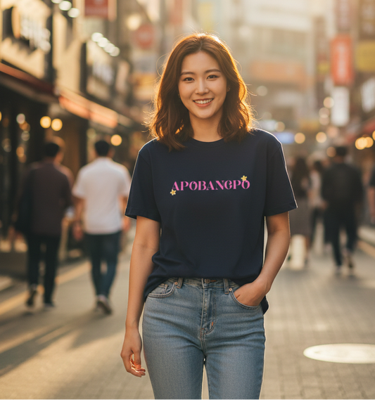 Woman wearing a black t-shirt with 'APOPANG' on a city street at sunset.